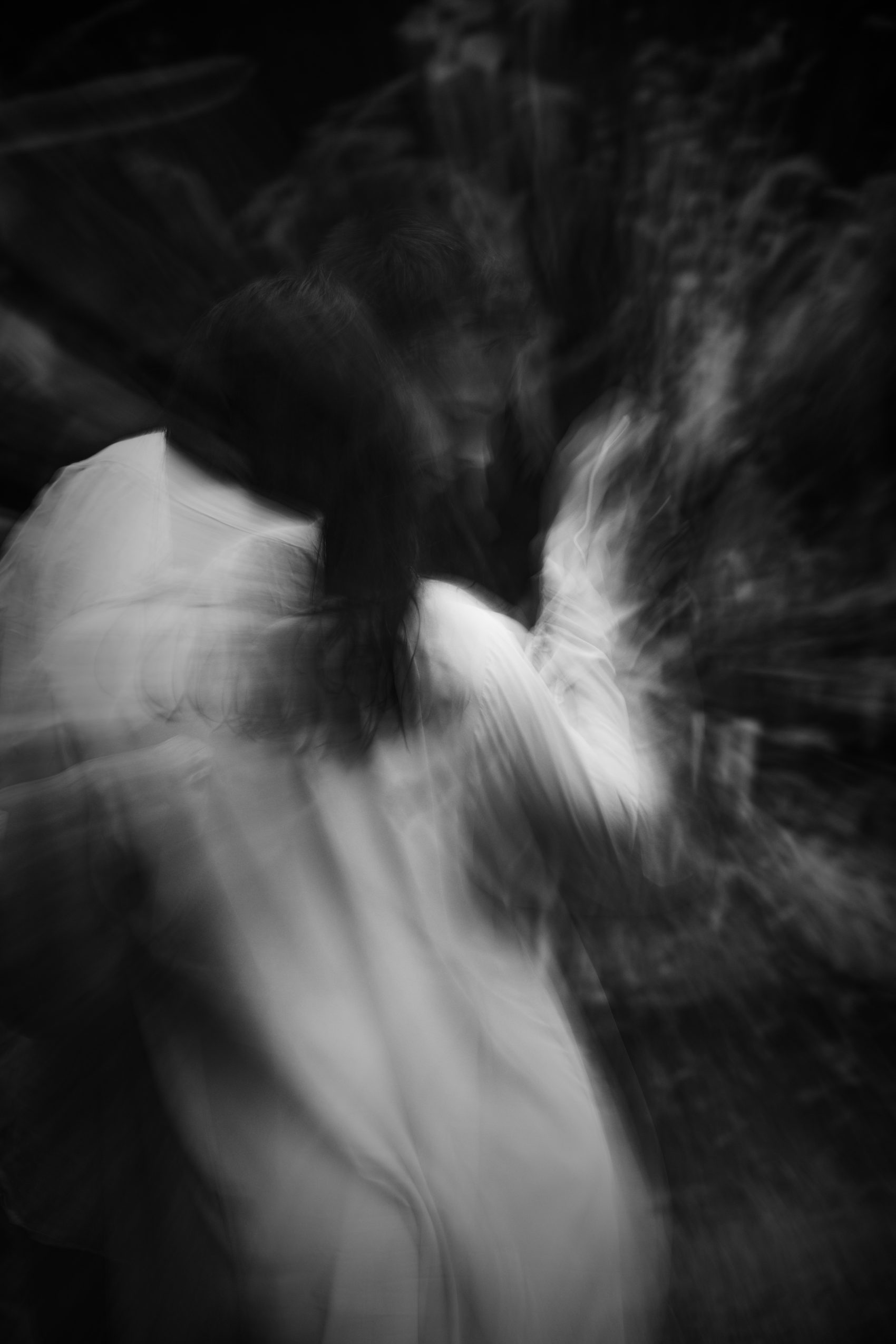 Two dancers moving together in long exposure, black and white