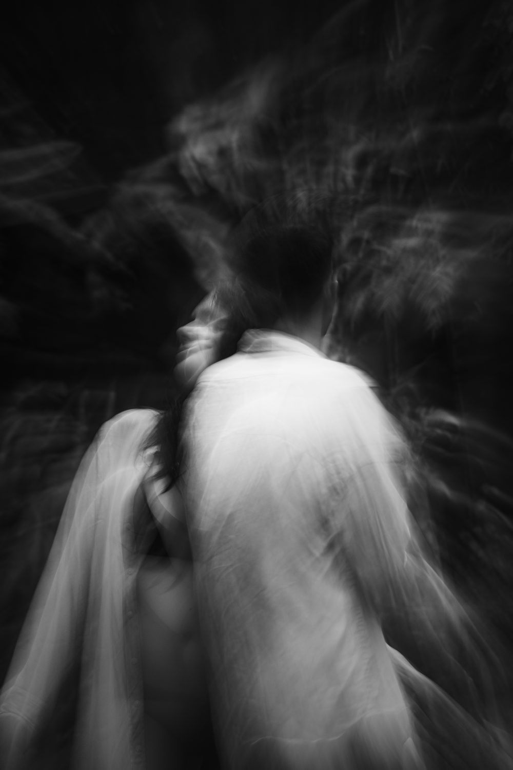 Two dancers folded together in the dark, black and white