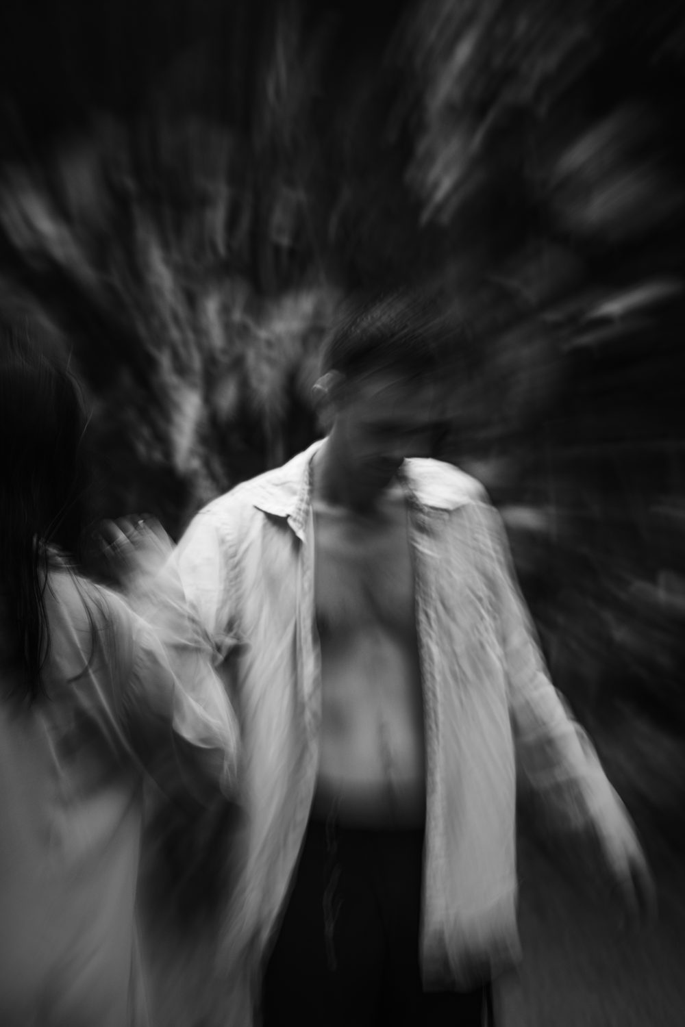 A dancer mid-turn, shirt open, long-exposure black and white